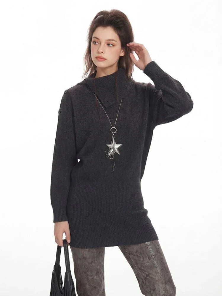 Side profile of a woman wearing a charcoal grey knit turtleneck tunic sweater and a star pendant necklace.