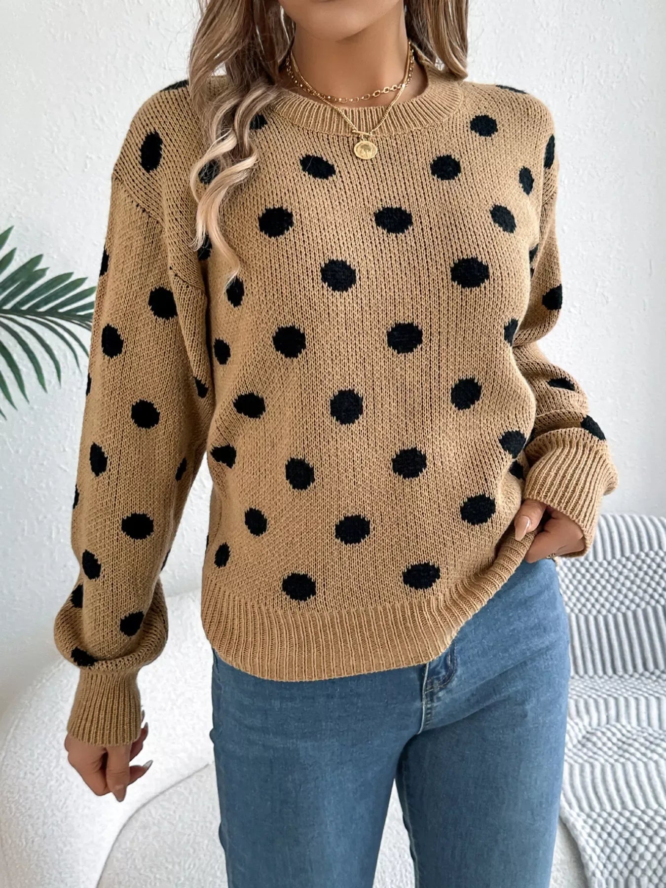 Close-up of a woman's torso wearing a tan polka dot sweater with visible knit texture.
