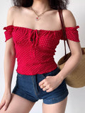 Woman wearing a red off-the-shoulder top with a white heart print and tie front.