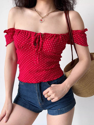 Woman wearing a red off-the-shoulder top with a white heart print and tie front.