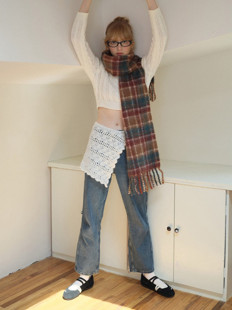 Woman wearing a plaid scarf with fringed edges.