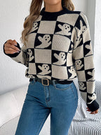 Close-up of a woman's torso wearing a black and cream checkerboard knit sweater with ghost print, blue jeans, and a black belt.