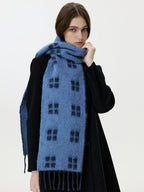 Close-up of a woman wearing a blue scarf with a black windowpane plaid pattern