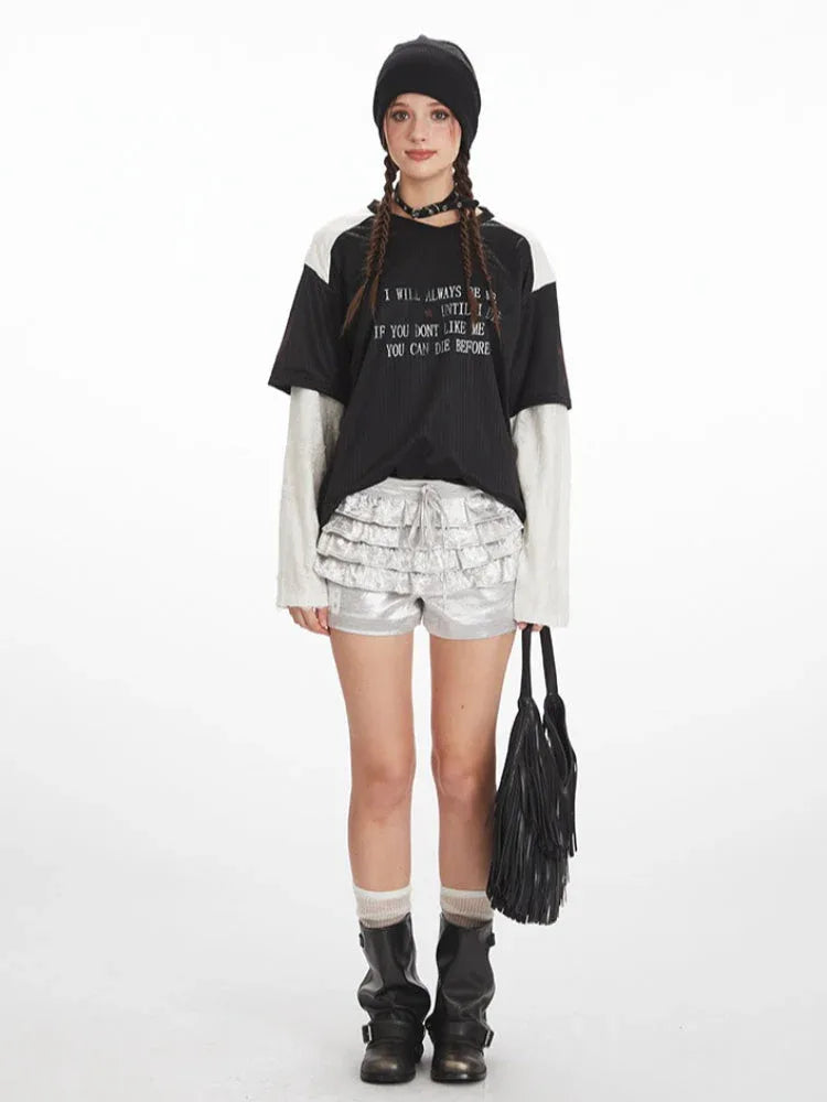 Model wearing a black and white long sleeve graphic t-shirt with silver ruffled shorts.