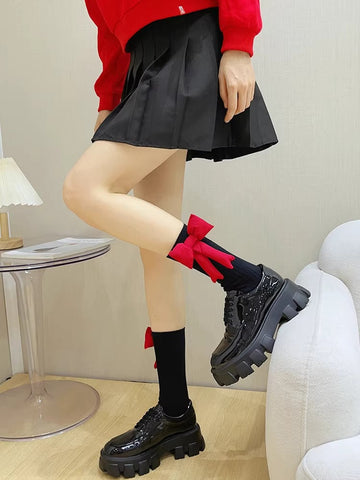 Woman wearing black crew socks with red bow accents