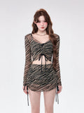 Woman wearing a sheer striped long-sleeve crop top and matching ruched mini skirt