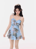 Woman wearing a blue abstract print dress with a ruffled neckline and tiered skirt
