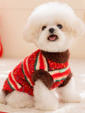 White Bichon Frise dog wearing a red, green, and white striped knit sweater with brown fuzzy trim.