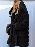 Woman wearing a black hooded faux fur coat with horizontal paneling.