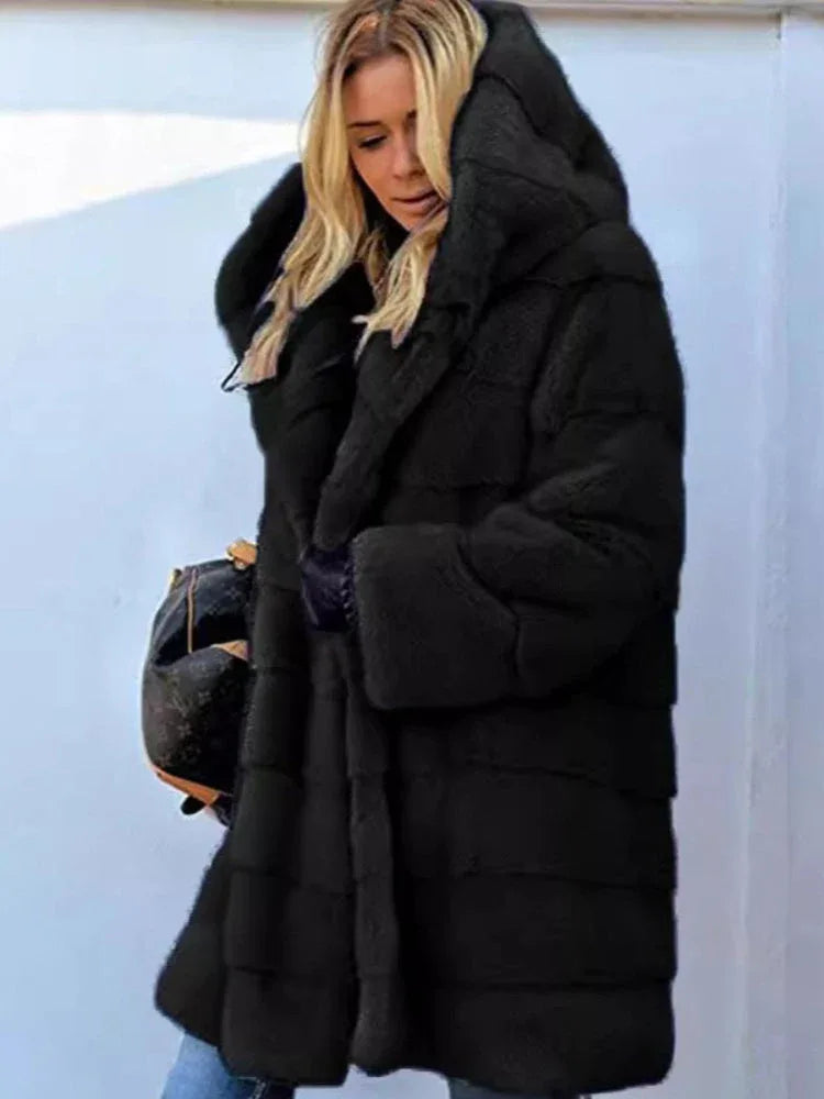 Woman wearing a black hooded faux fur coat with horizontal paneling.