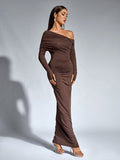 Full-length front view of a woman in a brown one-shoulder draped maxi dress