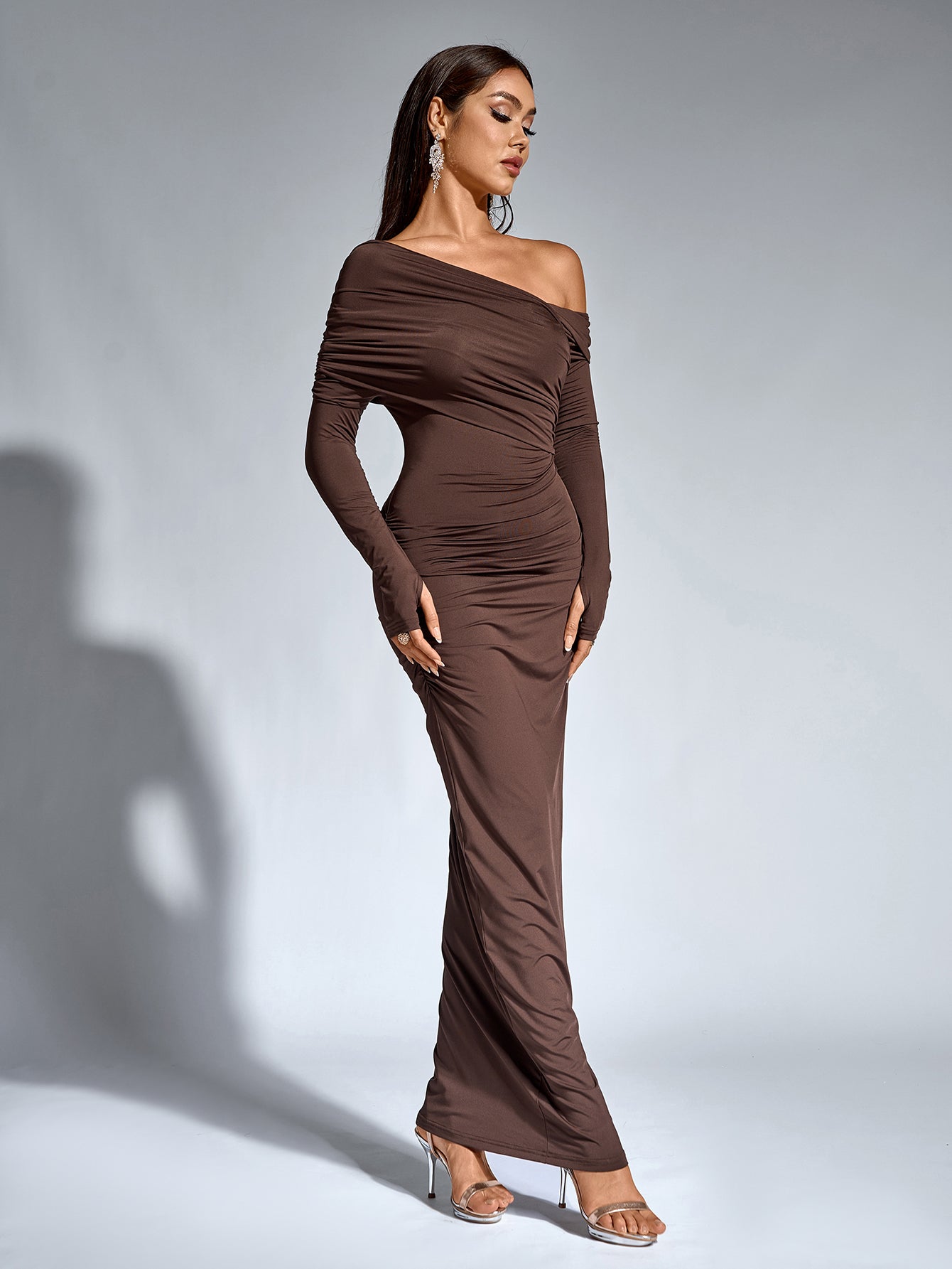 Full-length front view of a woman in a brown one-shoulder draped maxi dress