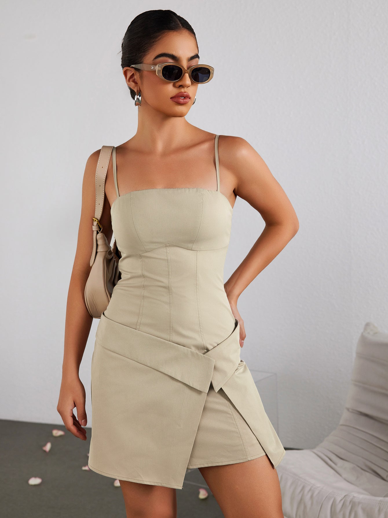 Woman wearing a beige sheath dress with spaghetti straps and an asymmetrical hem