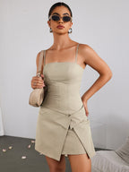 Front view of a woman in a beige sheath dress holding a handbag