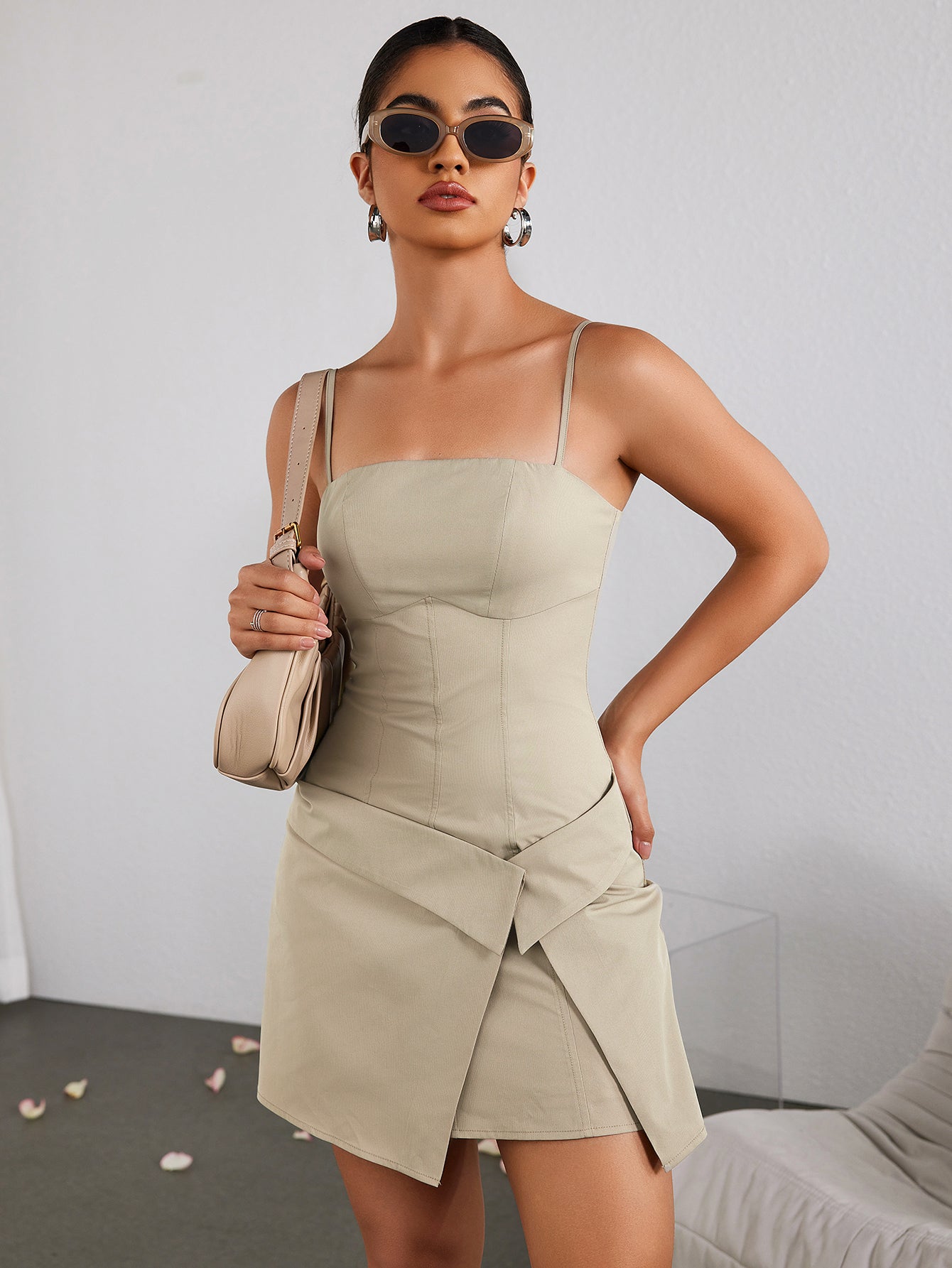 Front view of a woman in a beige sheath dress holding a handbag