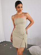 Woman in a beige dress with hands on hips, looking down