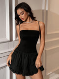 Woman wearing a black mini dress with spaghetti straps and a tiered skirt.