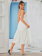 Woman in a black crepe sheath dress with a sweetheart neckline, hands raised to her hair.