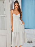 Woman wearing a black crepe sheath dress with a sweetheart neckline and spaghetti straps.