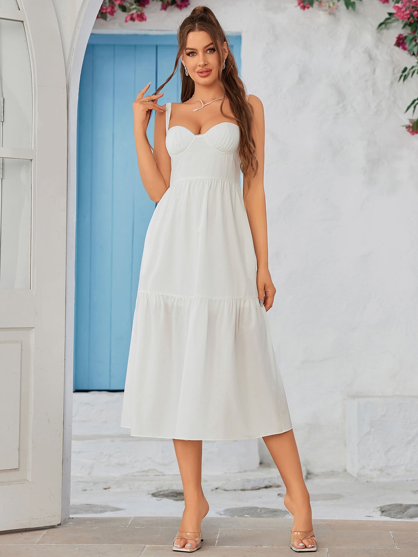 Rear side profile of a woman in a black crepe sheath dress with a sweetheart neckline.