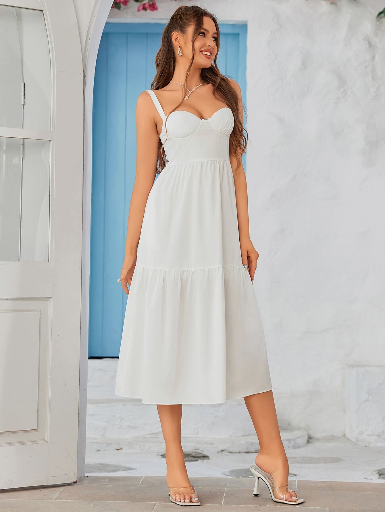 Side profile of a woman in a black crepe sheath dress with a sweetheart neckline, one hand in pocket.