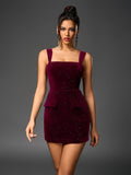 Woman in a short, deep red velvet dress with spaghetti straps and sparkling embellishments, walking forward.