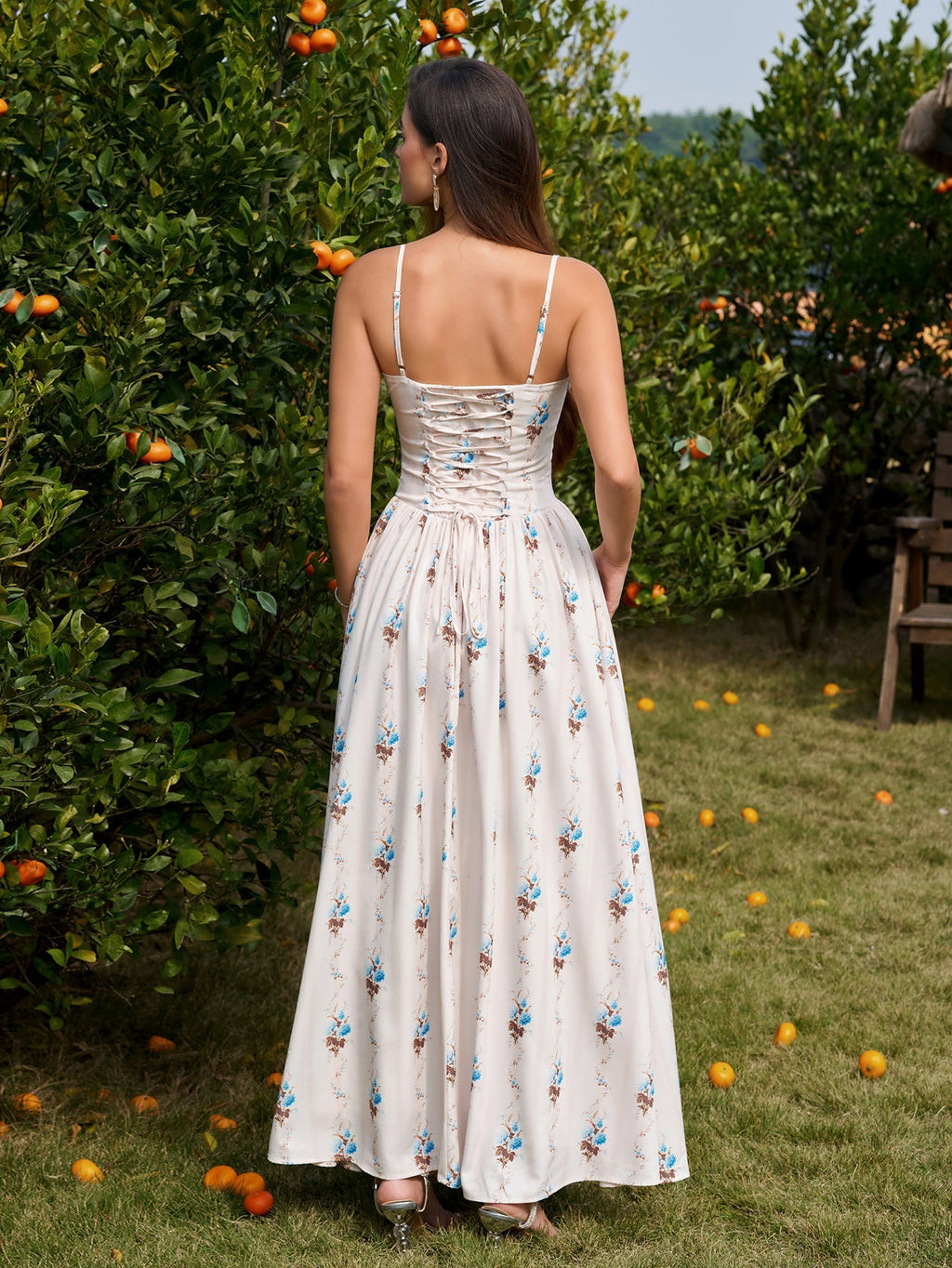Back view of a woman in a white floral print maxi dress with a lace-up corset detail at the back.