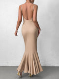 Back view of a woman in a beige ribbed knit maxi dress showing the backless design
