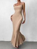 Side profile of a woman wearing a beige ribbed knit fishtail maxi dress