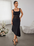 Woman wearing a black sleeveless dress with a square neckline and sheer mesh waist detail, standing in a room with white curtains and floral arrangements.