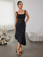Woman wearing a black sleeveless dress with a square neckline and sheer mesh waist detail, standing in a room with white curtains and floral arrangements.