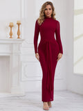 Front view of a woman in a long red formal dress with a tie waist detail and mock neck.