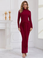 Front view of a woman in a long red formal dress with a tie waist detail and mock neck.