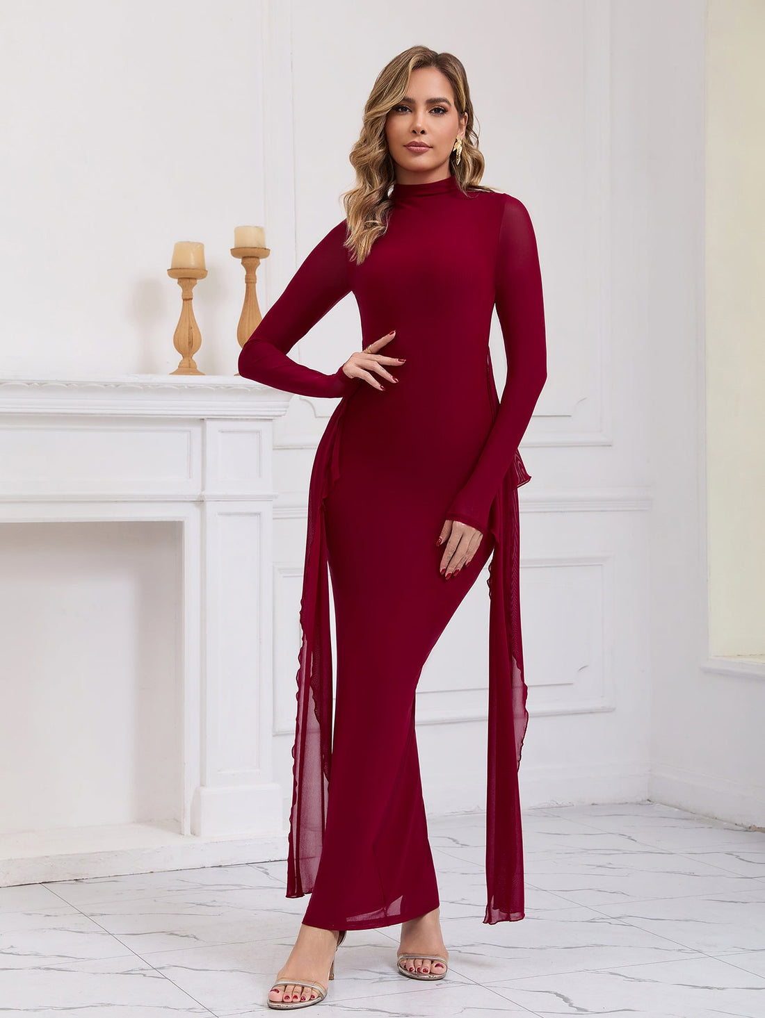 Woman wearing a long red formal dress with sheer sleeves and draping chiffon panels.