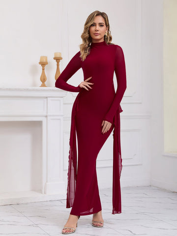 Woman wearing a long red formal dress with sheer sleeves and draping chiffon panels.