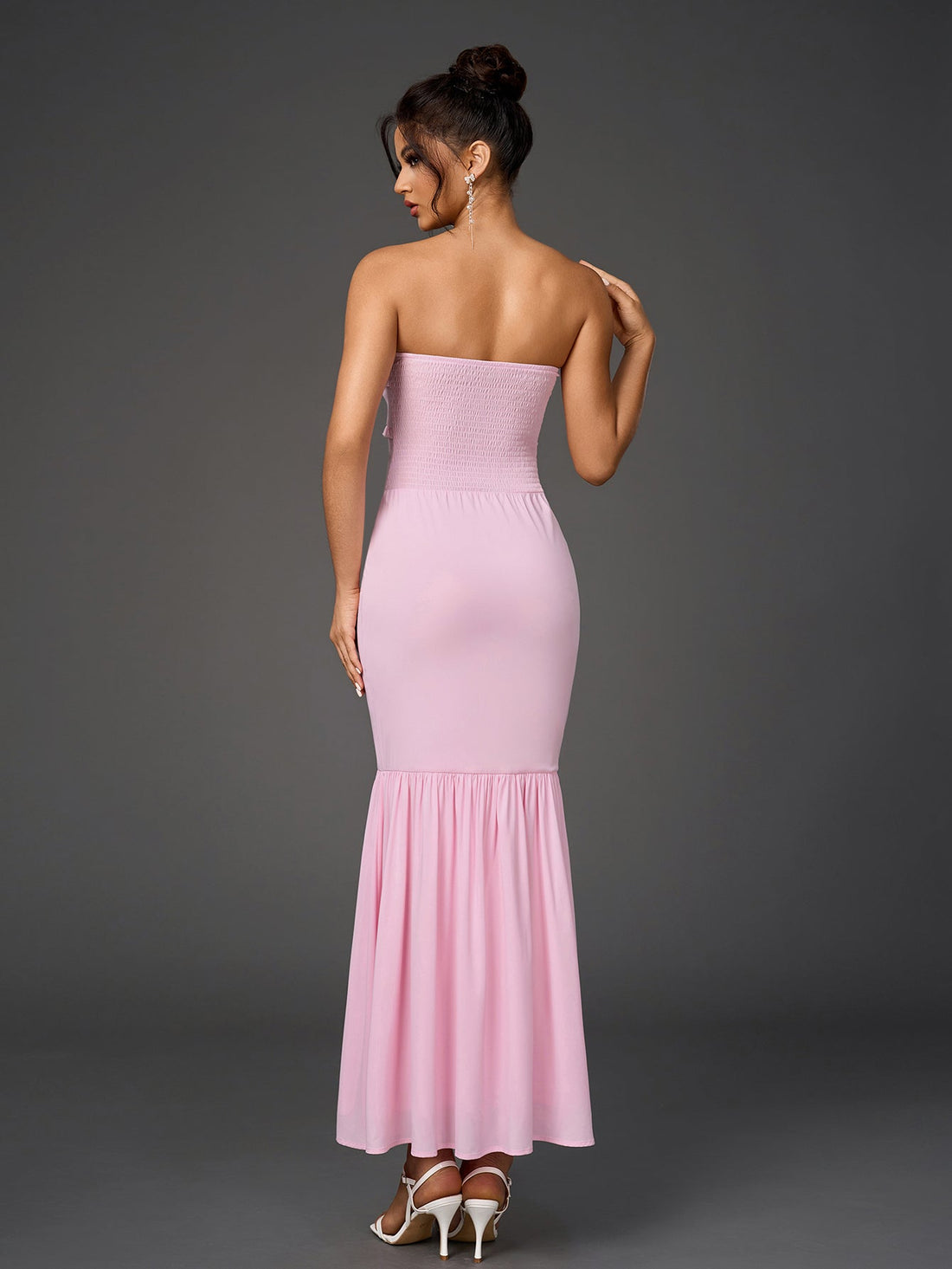 Woman wearing a pink strapless mermaid gown with a ruffled neckline.