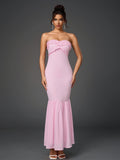 Front view of a woman in a pink strapless mermaid gown with ruffled details.
