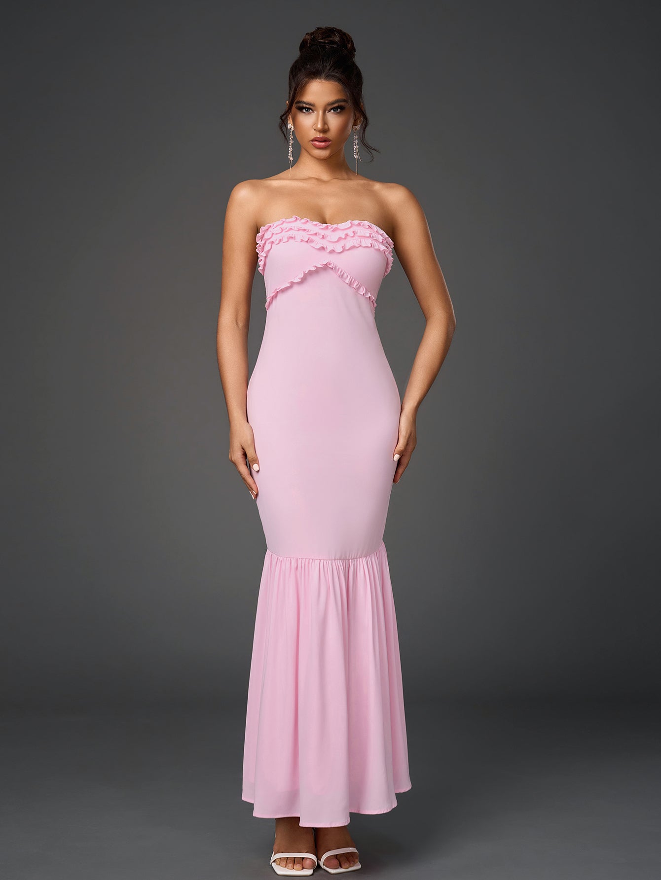 Front view of a woman in a pink strapless mermaid gown with ruffled details.