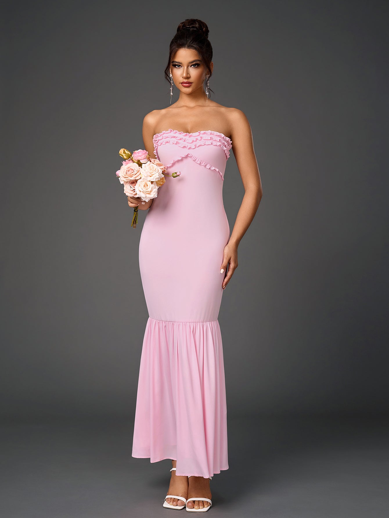 Woman wearing a pink strapless mermaid gown with a ruffled neckline.