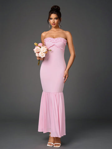 Woman wearing a pink strapless mermaid gown with a ruffled neckline.