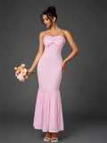 Woman holding a bouquet of roses while wearing a pink strapless mermaid gown.