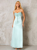 woman wearing a light blue satin maxi dress with spaghetti straps and a ruched, tie-front neckline