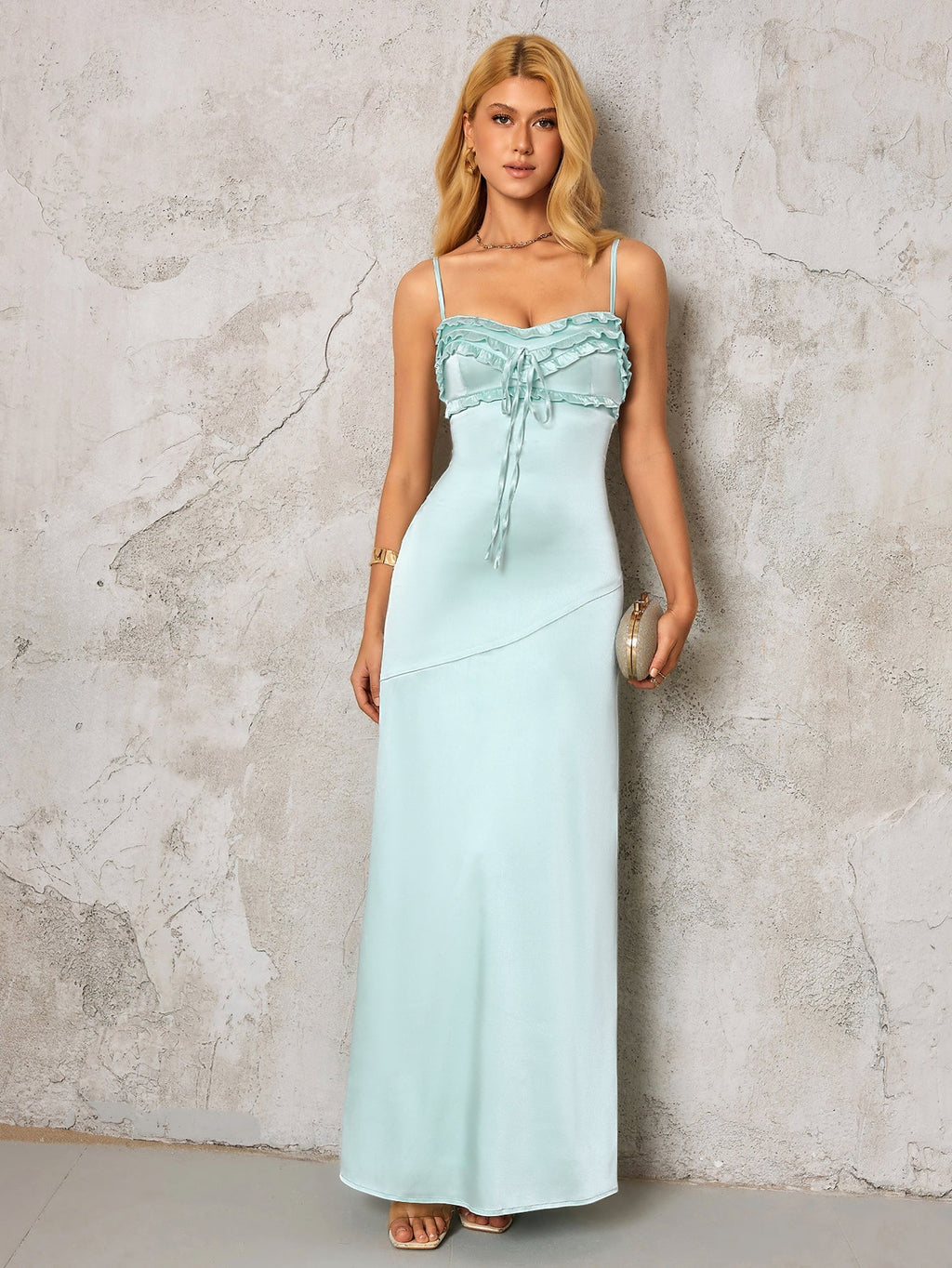 woman in a light blue satin maxi dress holding a gold clutch
