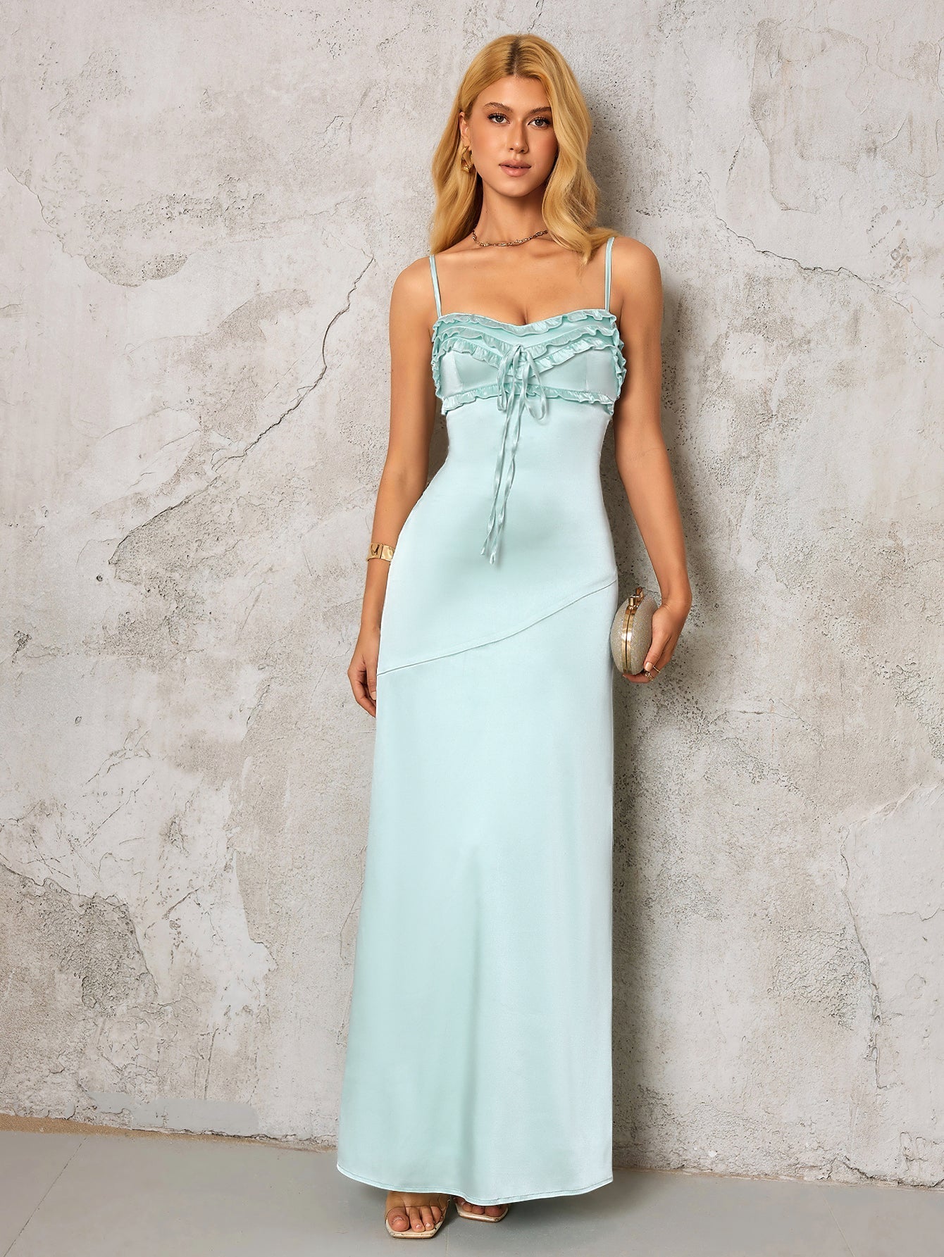 woman in a light blue satin maxi dress holding a gold clutch