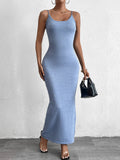 Woman in a blue shimmer knit bodycon maxi dress with cami straps and a scoop neckline, holding a black handbag.