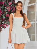 Front view of a woman in a white sleeveless mini dress with a square neckline and pleated skirt, smiling.