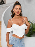Woman wearing a white off-the-shoulder corset crop top with spaghetti straps and ruffled sleeves, paired with light wash denim jeans.