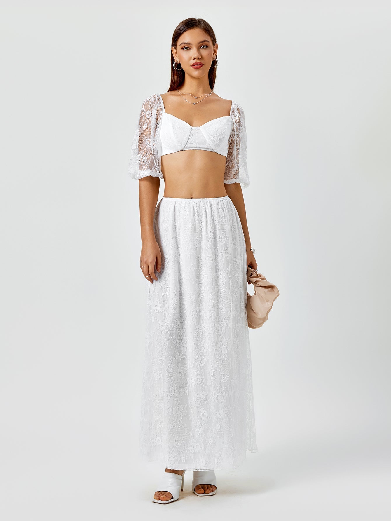 Woman wearing a white lace cropped top with puff sleeves and a matching white lace maxi skirt