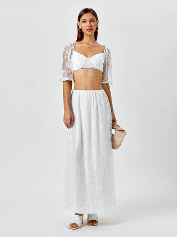 Woman wearing a white lace cropped top with puff sleeves and a matching white lace maxi skirt
