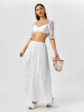 Woman holding a beige clutch while wearing a white lace set